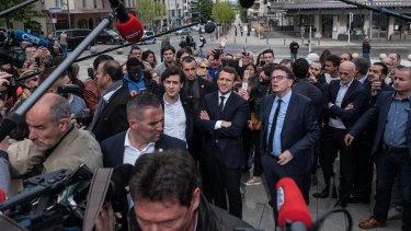 Emmanuel Macron is surrounded by journalists as he campaigns.