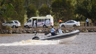 A police boat patrols on the Tweed River near Tumbulgum, where a three people are feared dead after their car was swept away on Monday.