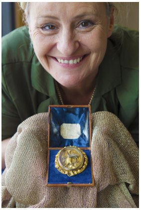 MADE Ballarat curator Cash Brown is holding an Australian reversible gold and silver brooch with glass dome and cameo.