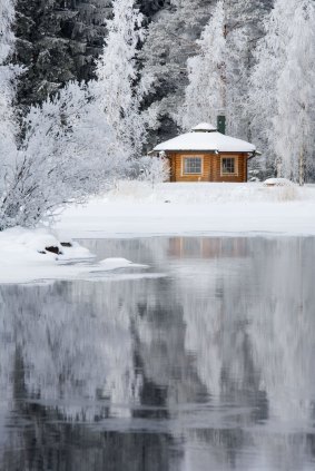 A wooden sauna cabin on a riverbank in Finland.