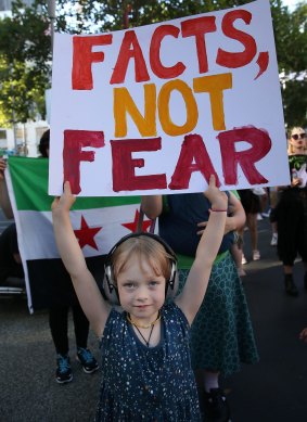 A child joins protests in Melbourne against Trump's travel ban affecting citizens from seven Muslim-majority countries. 