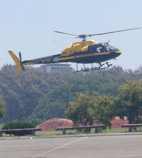 A helicopter lifts off in hazy conditions on Saturday at the Sea World car park. Emergency services are battling a fire on the Gold Coast which had led to the evacuation of the theme park and resort, and some road closures.