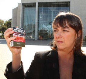 Former attorney-general Nicola Roxon holds a pack of cigarettes with plain packaging.