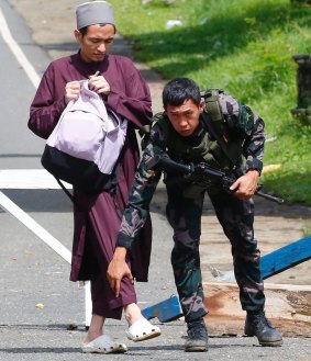 Government troops frisk a Muslim man at a checkpoint leading to Marawi city.