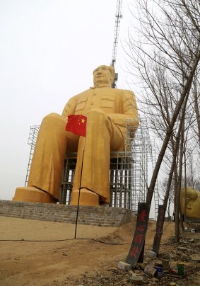 A Chinese flag flies next to a 36.6-metre-tall gold-coloured statue of former Chinese leader Mao Zedong in Tongxu County in central China's Henan province. 