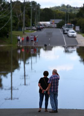 Local residents stand near rising flood waters in Kokoda Street on April 1 at Beenleigh.