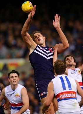 Docker Aaron Sandilands taps the ball, with Bulldog Tom Liberatore hanging on to his arm at a ruck contest.