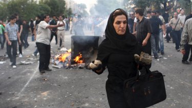 An Iranian woman carries rocks at a protest in Tehran during the 2009 Green Movement. 