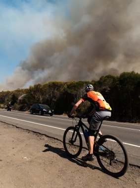 A cyclist along the Wakehurst Parkway as hazard-reduction burns get going.
