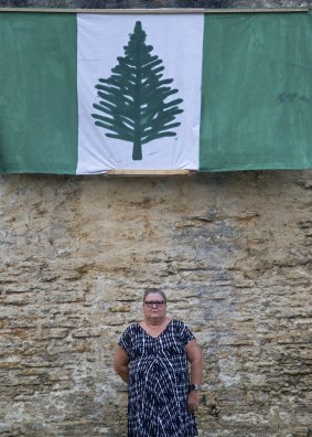 Kim Edward under a Norfolk Island flag at the site of the axed Norfolk Island Legislative Assembly.