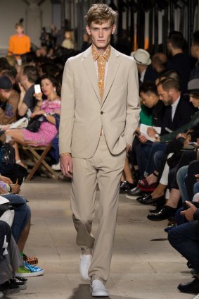 A model from the Hermes Spring 2015 show pairs an unstructured suit with a relaxed pair of sneakers. 