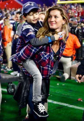 Gisele Bundchen, wife of  Tom Brady of the New England Patriots, walks on the field with their son, Benjamin.