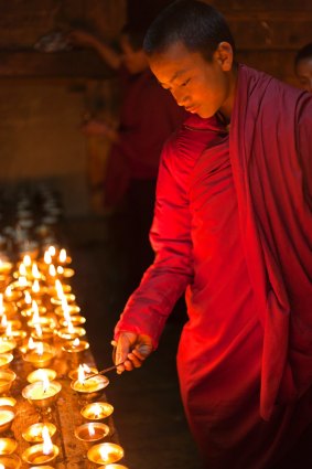 A young monk lighting butter lamps at Gangtey Gompa. 