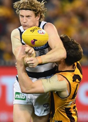 The Cats' Josh Caddy handballs while being tackled by Hawk Ben Stratton in a qualifying final.