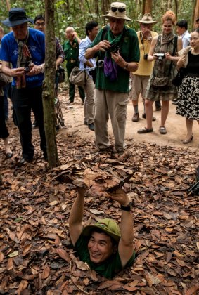A Vietnamese tour guide demonstrates how to disappear into the Cu Chi tunnels through a camouflaged hole during a tour at the Cu Chi tunnels.