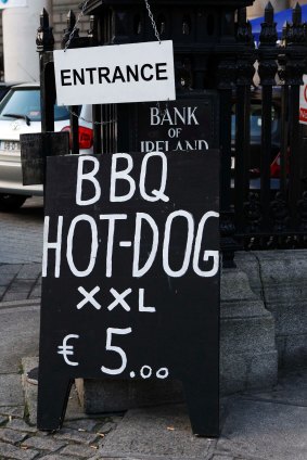 A sign advertising for barbecued food rests against the entrance to the Bank of Ireland headquarters in Dublin in 2010. WHO says over-eating is causing a major health problem for the Irish.