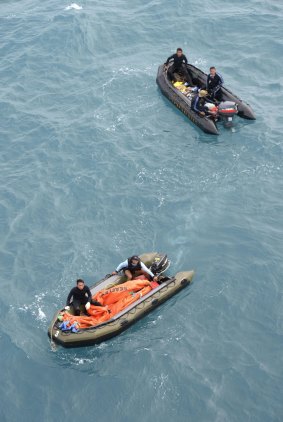 Crew members from an Indonesian navy vessel prepare to conduct operations to lift the tail of AirAsia QZ8501 in the Java sea. 