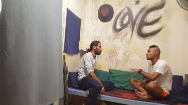 Behrouz Boochani, left, interviews a fellow asylum seeker in <i>Chauka, Please Tell Us the Time</i>.