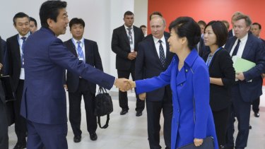 South Korean President Park Geun-hye, right, and Japanese Prime Minister Shinzo Abe, second left, shake hands as Russian President Vladimir Putin watches during the Eastern Economic Forum in Vladivostok.
