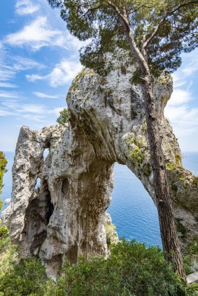Arco Naturale (Natural Arch), a Paleolithic rock formation towering over the inky-blue Tyrrhenian Sea. 