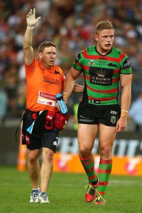 George Burgess of the Rabbitohs is escorted from the field after a head clash with Josh Jackson.