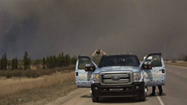 People stop to take photos of a wildfire south of Fort McMurray, Alberta.