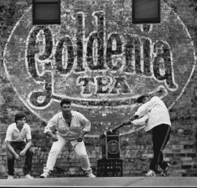 A Goldenia Tea sign in Leichhardt acts as a backdrop for an impromptu cricket match. 
