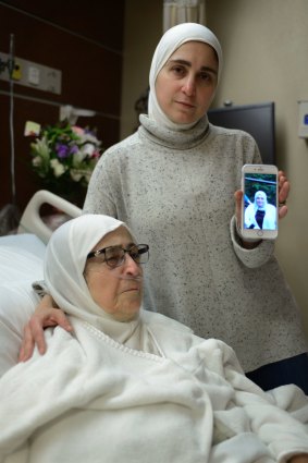 Nour Ulayyet holds her smartphone with a photo of her sister Sahar al-Gonaimi, who was not permitted to enter the United States, while comforting her ill mother Isaaf Jamal Eddin at Munster Community Hospital in Munster, Indiana, on Saturday.
