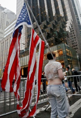 Lone protester Sarah, who refused to give her last name, stands outside Trump Towers holding a shredded US flag, demonstrating her opposition to Trump becoming President.