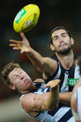 Brodie Grundy gets a hand to the ball ahead of Mark Blicavs of the Cats.
