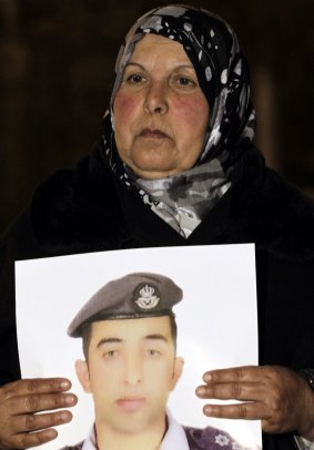 The mother of Jordanian air force pilot Maaz al-Kassasbeh carries a portrait of her son during a protest. 