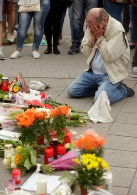 People mourn near the crime scene at OEZ shopping centre the day after the shooting spree.