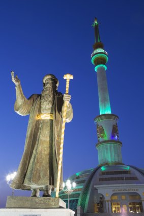 Statue in front of Independence Monument at dusk, Ashgabat, Turkmenistan.

