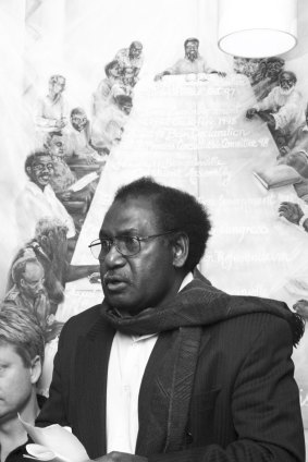 Moses Havini speaking at the opening of an exhibition of artwork by his wife, Marilyn, in 2004. Behind Moses is a painting of members of the Autonomous Government of Bougainville.