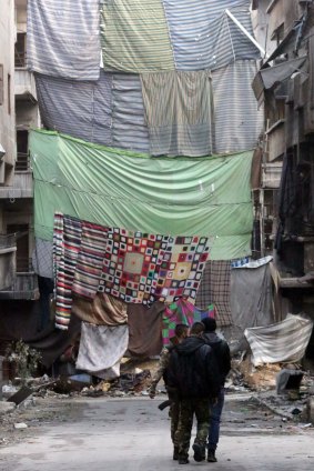 Rebel fighters in the Syrian city of Aleppo walk down a street protected by curtains to obstruct the view of snipers.