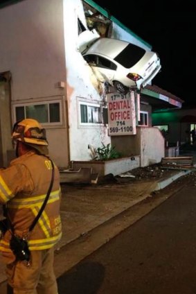 A car that crashed into a building in Santa Ana, California, hangs from the second-storey.
