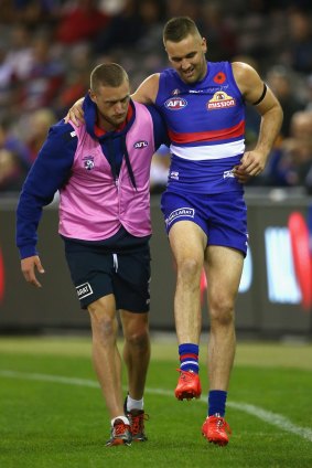 Matt Suckling is helped from the ground by a trainer after injuring his knee.