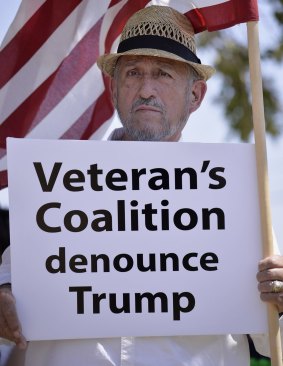 Retired teacher Adolfo Gonzalez, a 39-year army veteran, holds a sign denouncing presidential candidate Donald Trump at Laredo International Airport.