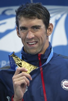 Michael Phelps holds up his men's 100m butterfly gold medal at the Pan Pacific Swimming Championships held on the Gold Coast in August.