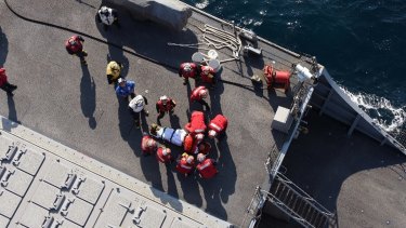 US military personnel prepare to transfer an injured person from the USS Fitzgerald.