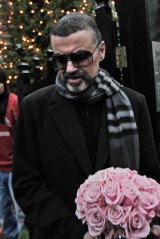 In this 2011 photo, George Michael leaves his house in north London after recovering from a life-threatening bout  of pneumonia.