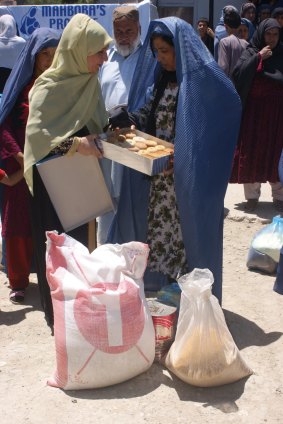 Mahboba Rawi (left) distributes food supplies to widows in Afghanistan.