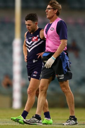 Hayden Ballantyne walks from the field with the club doctor after stumbling on the recently relaid turf.