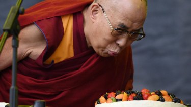The Dalai Lama blows out a candle on a cake to celebrate his 80th birthday as he visits the Glastonbury Festival.