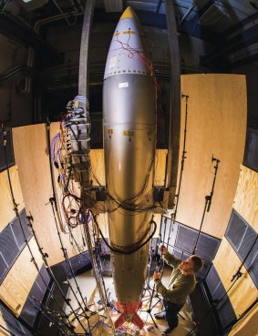 Sandia Labs mechanical engineer Ryan Schultz adjusts a microphone for an acoustic test on a B61-12 nuclear bomb surrounded by banks of speakers that expose it to an acoustic field. 