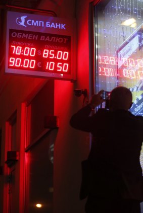 A shocked man takes a picture of a board showing currency exchange rates in Moscow on Tuesday. 
