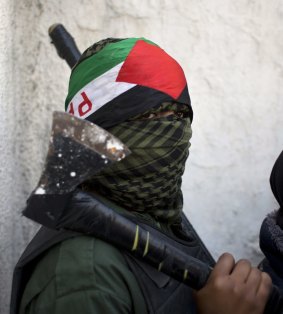 A masked Palestinian youth carries an axe at the funeral of 13-year-old Palestinian Ahmad Sharaka in the Jalazoun refugee camp, near the occupied West Bank city of Ramallah.