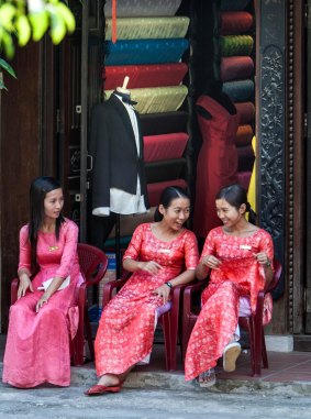 Young women sit outside a tailor shop in Hoi An.