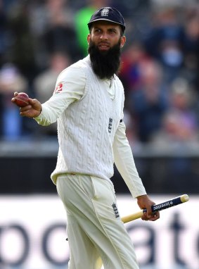 England's Moeen Ali walks off the pitch with the ball and a stump, after taking 5-69.