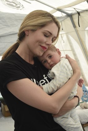 Tara Moss gives eight-month-old Nour a cuddle after she receives her oral polio vaccine in a mobile health clinic that visits each informal refugee settlement just once a month.